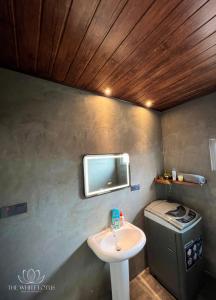 La salle de bains est pourvue d'un lavabo, de toilettes et d'une télévision. dans l'établissement White Lotus Apartments, à Dankotuwa