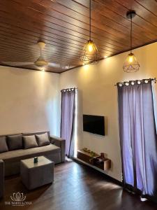 - un salon avec des rideaux violets et un canapé dans l'établissement White Lotus Apartments, à Dankotuwa