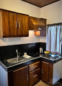 une cuisine avec des armoires en bois et un évier dans l'établissement White Lotus Apartments, à Dankotuwa