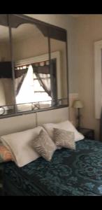 Un dormitorio con una cama con dos almohadas y un espejo. en Departamento temporario, en La Plata