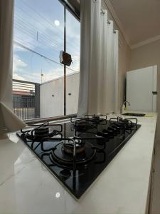 a black stove top in a kitchen with a window at Lar Aconchegante 2min do centro in Primavera do Leste +18 photos