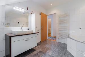 a white bathroom with a sink and a tub at homy Alpenlodge in Innerbraz