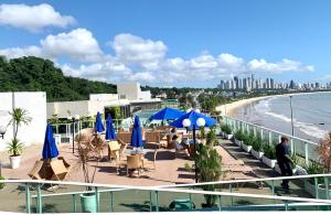 un balcone con tavoli e ombrelloni blu e una spiaggia di Flat JP Beira mar a João Pessoa
