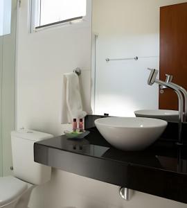 a bathroom with a black counter with a sink and a toilet at Flats Premium Jabaquara in Paraty