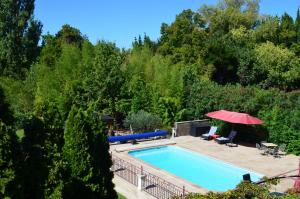 a swimming pool in a yard with a red umbrella at Studio de la Luciole in Mouriès