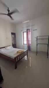a bedroom with a bed in a room with a fan at Sinai Homestay in Trivandrum