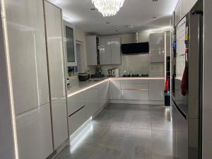 una cucina bianca con armadi bianchi e lampadario pendente di Moore Place a Houghton Regis