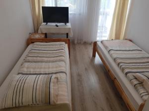two beds in a room with a tv and a desk at Bobowianka in Bobowa