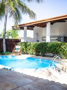 a swimming pool with a chair and palm trees at Kite Oasis Parajuru Casa Branca in Parajuru