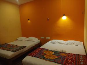 ゴカルナにあるKudle Heavenのオレンジ色の壁の部屋にベッドが2つある