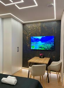 a living room with a table and a television on a wall at Zielona Ostoja - Pokoje i Apartamenty in Nowa Sarzyna
