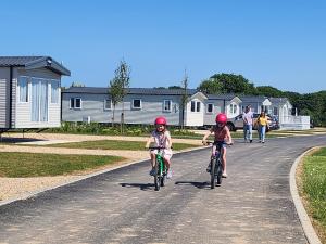 two children are riding bikes down a road at Hayling Island Holiday Park in South Hayling