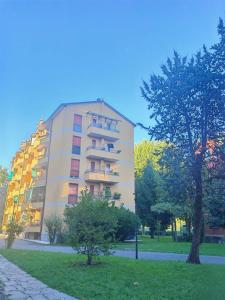 米兰Milan Parco Nord Casa的一座高大的公寓楼,前面有一棵树