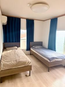 two beds in a room with blue curtains at Karwan House in Wako
