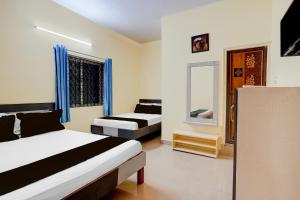 a bedroom with two beds and a mirror at Hotel O Bluestar in Bangalore