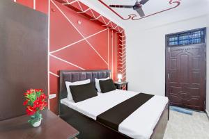 a bedroom with a bed and a red wall at Hotel O Kp Guest House in Bāra Banki