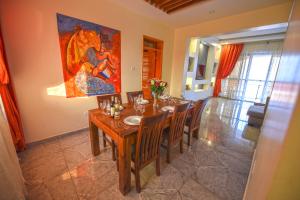 einen Esstisch mit Stühlen und ein Gemälde an der Wand in der Unterkunft Bon Bini Residence in Kampala