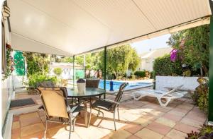 un patio con tavolo e sedie e una piscina di Acogedora casa de invitados a Hinojos