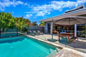 a swimming pool with an umbrella next to a house at Stonecutters 2 in Byron Bay