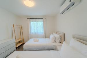 a white bedroom with two beds and a window at Stylish 3 Bedroom Villa with Garden, Chalong - by PoshSaga in Chalong 