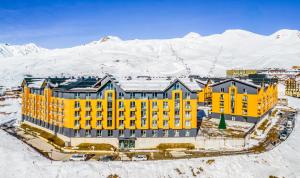 an aerial view of a yellow building in the snow at New Gudauri Four Seasons F3 by Gudauri Travel in Gudauri