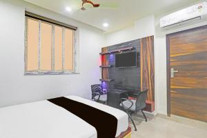 a bedroom with a bed and a desk and a tv at Collection O Sheesh Mahal Hotel in Patna