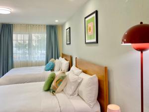 een slaapkamer met twee bedden met witte kussens en een rode lamp bij Gainesville Lodge in Gainesville