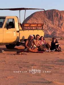 a group of people sitting next to a yellow truck at Bedouin Nights Camp in Wadi Rum