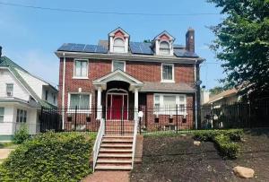 a large brick house with a red door and stairs at Modern loft 9 min from EWR in Hillside