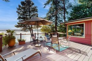 una terraza con sillas y una sombrilla en una casa en Hale Passage Beach House, en Gig Harbor
