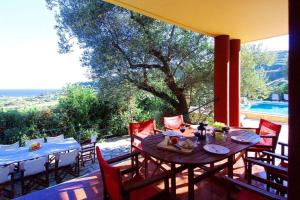 a patio with tables and chairs and a large window at Villa Aliona in Mavráta