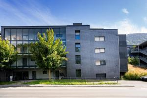 フェルトキルヒにあるhomy City Diamant in Feldkirch, Grenznähe und doch Zentralの木の目の前の灰色の建物