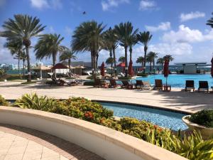 un complejo con piscina con palmeras y sillas en Dawn Beach JW Marriott, en Oyster Pond