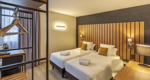 a hotel room with two beds and a desk at Best Western Côte des Sables Plouescat in Plouescat