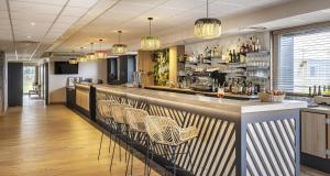un bar dans un restaurant avec des chaises en osier dans l'établissement Best Western Côte des Sables Plouescat, à Plouescat