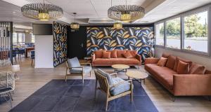 una hall con divani, tavoli e una parete colorata di Best Western Côte des Sables Plouescat a Plouescat