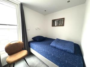 a small bedroom with a bed and a chair at Woonboot 1 - Maasterp in Montfort