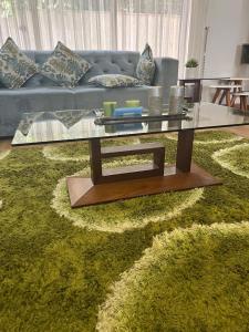 un soggiorno con un tavolo di vetro su un tappeto verde di Your Palace ad Addis Abeba