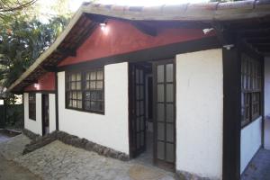 ein kleines rot-weißes Haus mit Fenstern in der Unterkunft Sitio Novo Dia in Saquarema