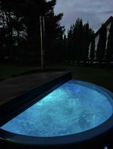 a large blue swimming pool in a yard at night at Domek nad Jeziorem z Jacuzzi na Mazurach 10os in Jedwabno