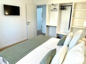 a bedroom with a large white bed with pillows at Gandia Tropicana Suite in Playa de Gandia
