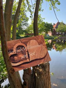 a sign hanging on a tree in front of a lake at Ferienwohnung am Parksee in Bad Bodenteich