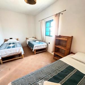 a bedroom with two beds and a window at Turquoise Brick Surf House in Essaouira