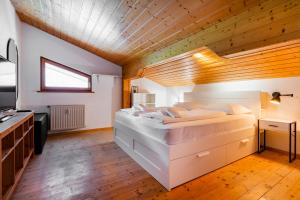 a bedroom with a large white bed with a wooden ceiling at homy Alpine Deluxe Chalet in St Anton im Montafon in Sankt Anton im Montafon