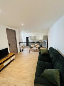 a living room with a green couch and a kitchen at City Loft Valence hyper-centre in Valence