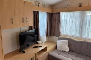 a living room with a couch and a flat screen tv at 2 Bedroom Chalet Sleeps 6 -Free Parking -Tv -WiFi in Chapel Saint Leonards