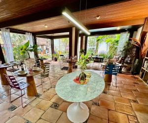 a large room with tables and chairs and windows at Hotel Casa Paradiso Guarujá in Guarujá