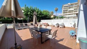 een terras met een tafel, stoelen en een parasol bij Cambrils Puerto in Cambrils