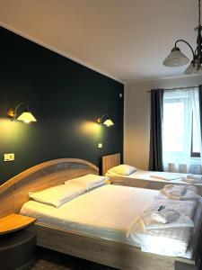 two beds in a bedroom with green walls at Pensiunea Elis in Pescari