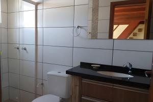 a bathroom with a toilet and a sink and a mirror at Residencial Flamboyant in Garopaba +58 photos